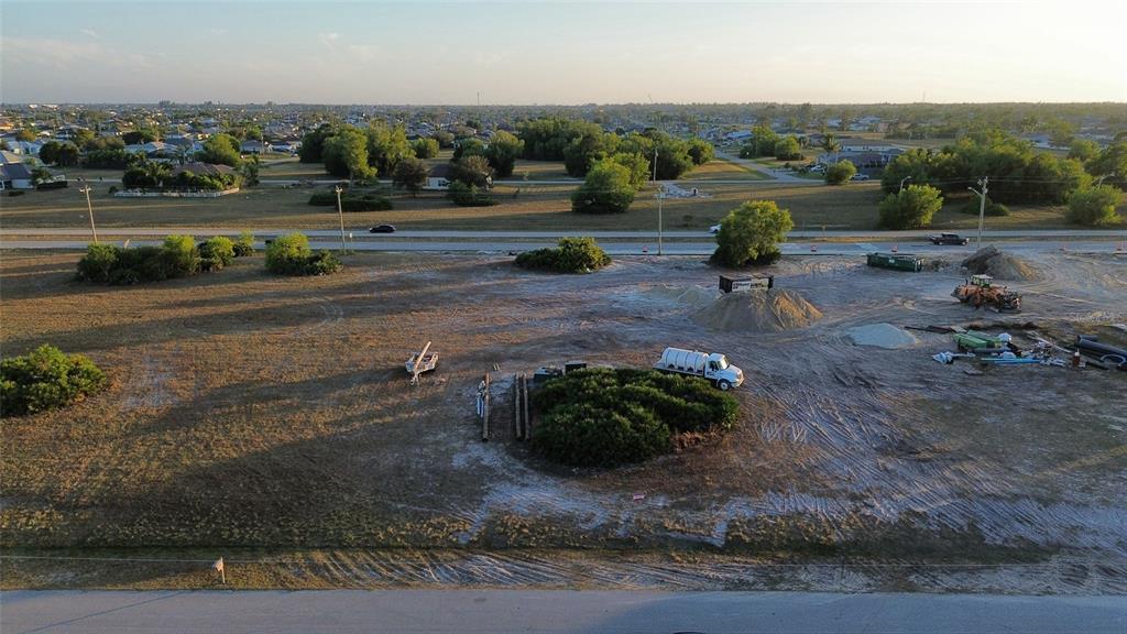 An aerial view shows a cleared, sandy construction lot with heavy equipment and a truck — 1508 NW 16TH TERRACE, CAPE CORAL, FL