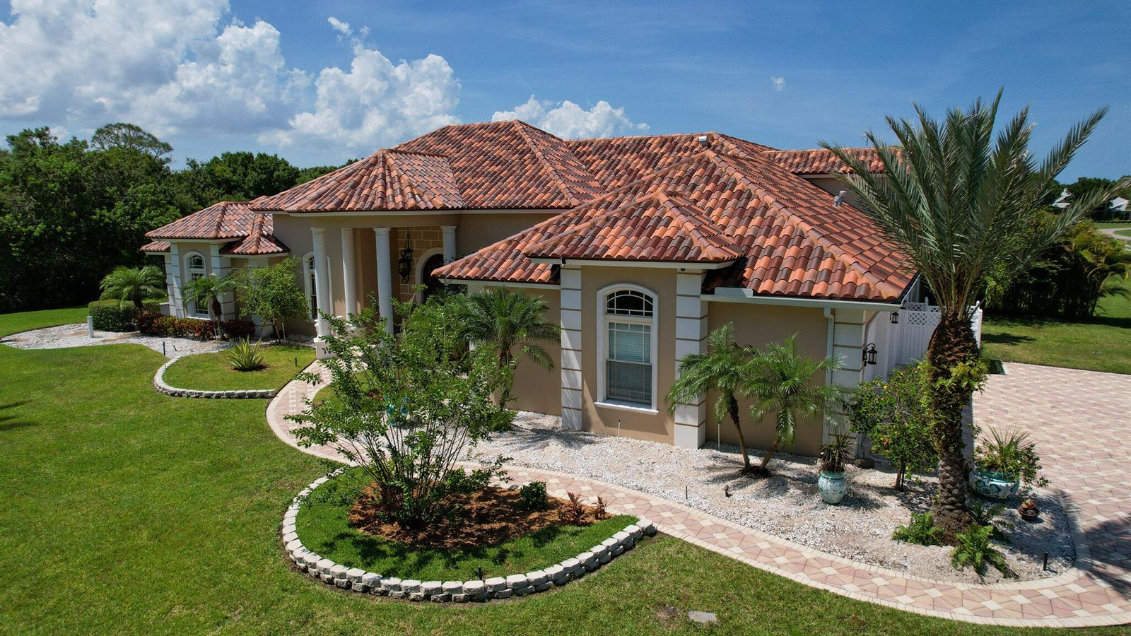 An aerial view of a tan house with a multi-gabled red tile roof and landscaping — 6780 49th Street, Vero Beach FL 32967, VERO BEACH, FL