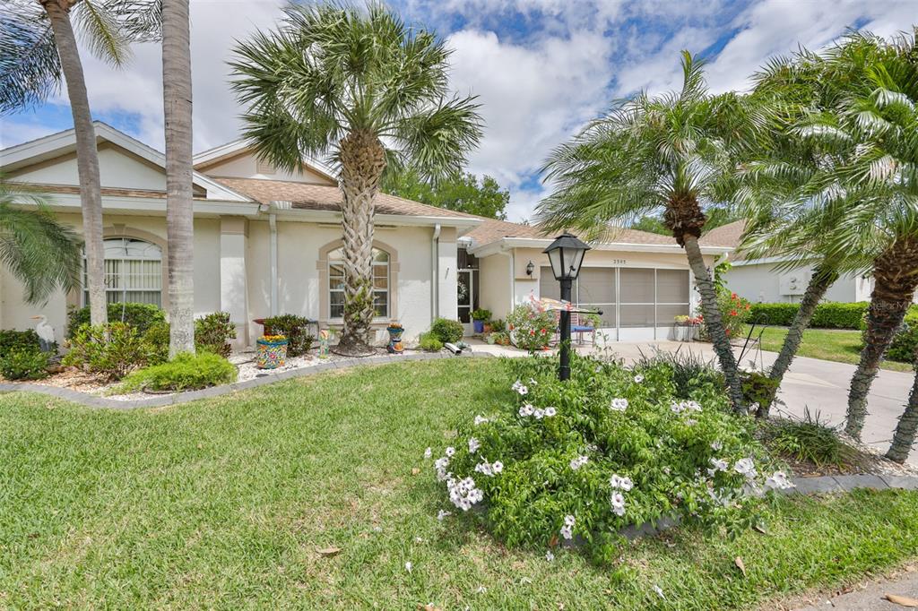 A single-story house with a tan exterior, palm trees, and a landscaped front yard — 2305 OLIVE BRANCH DRIVE, SUN CITY CENTER, FL