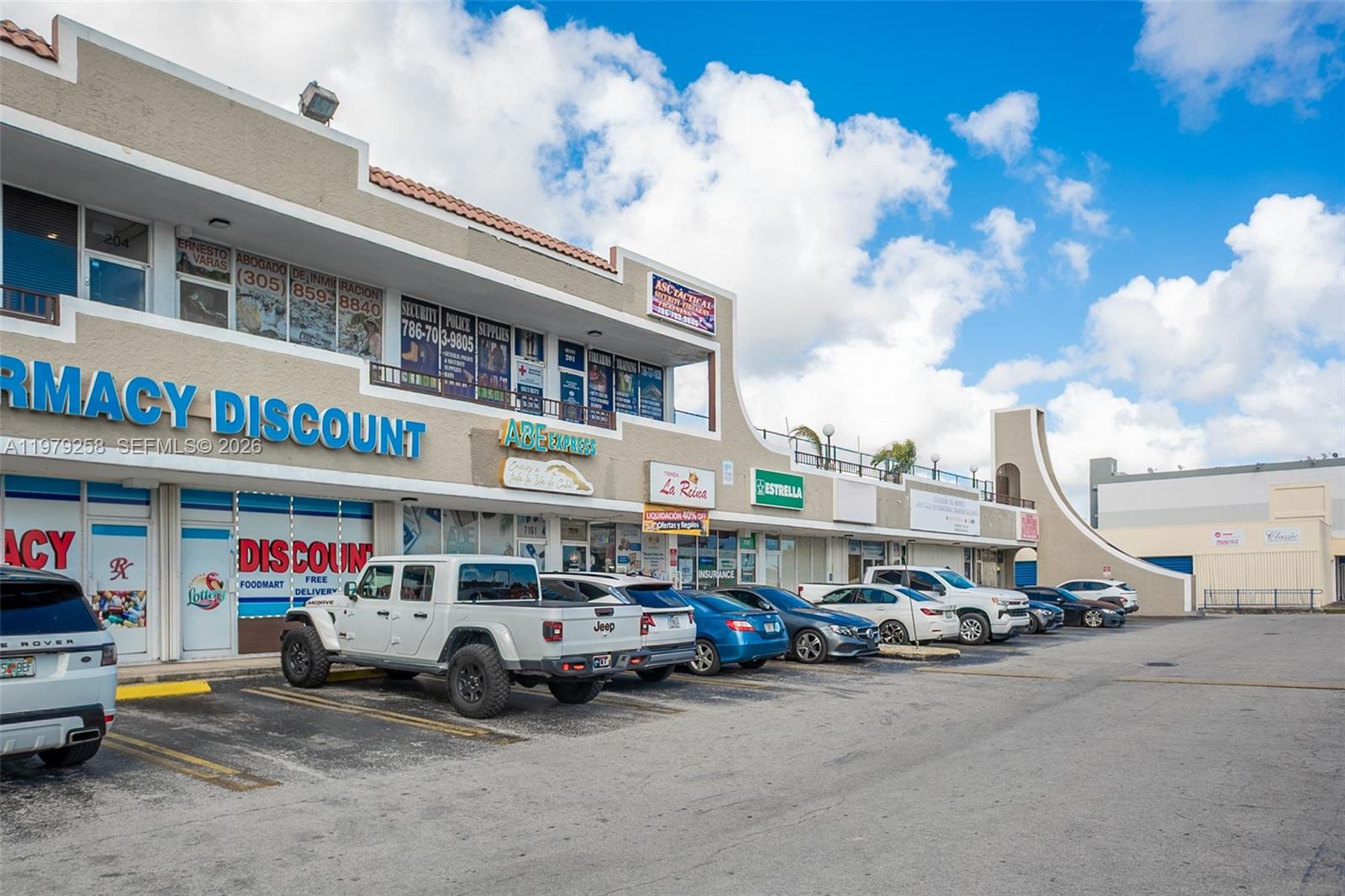 A two-story commercial strip mall with a parking lot in front under a blue sky — 7159 sw 8 st, Miami FL 33144, MIAMI, FL