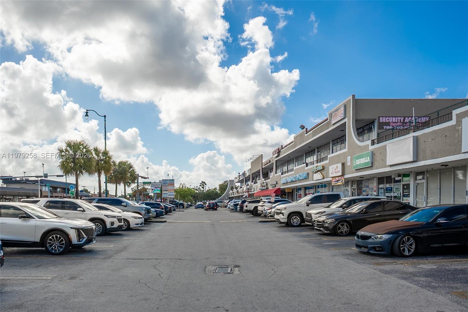 A parking lot sits in front of a multi-story commercial strip mall under a cloudy sky — 7159 sw 8 st, Miami FL 33144, MIAMI, FL