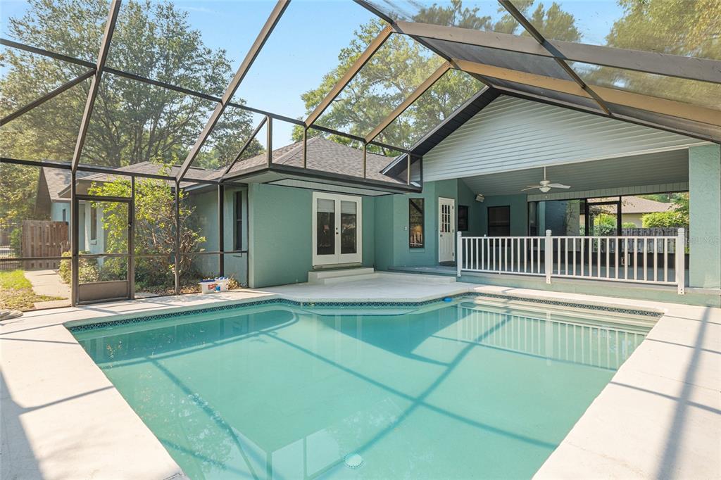 A backyard swimming pool with a screened-in enclosure and a covered patio area — 2023 SW 76TH TERRACE, GAINESVILLE, FL