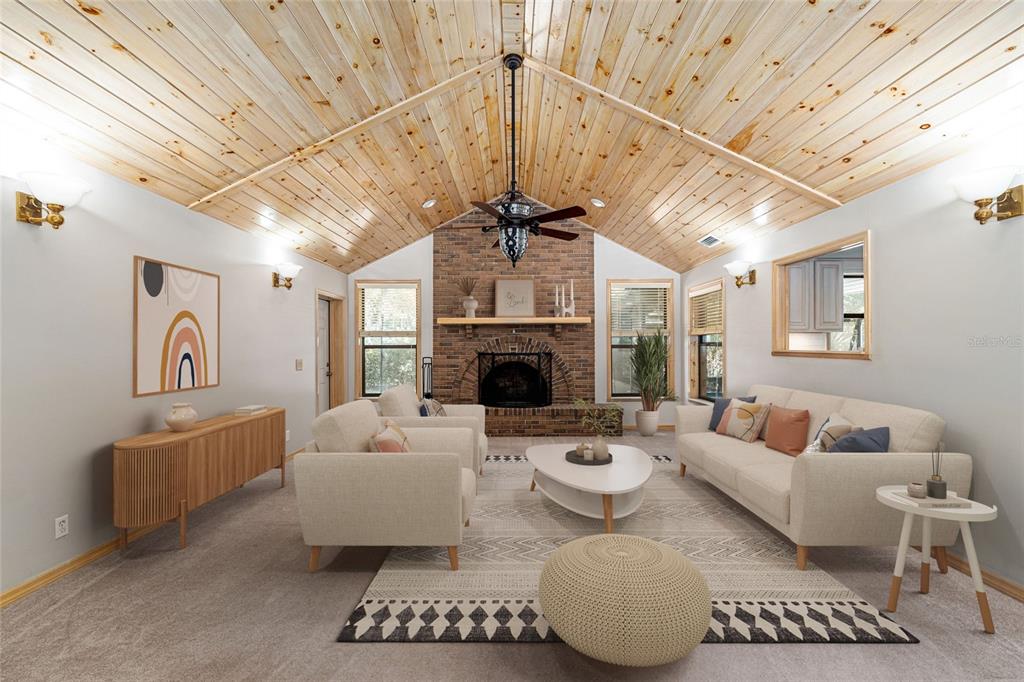 A living room features a vaulted wood-plank ceiling, a brick fireplace, and neutral-toned furniture — 2023 SW 76TH TERRACE, GAINESVILLE, FL
