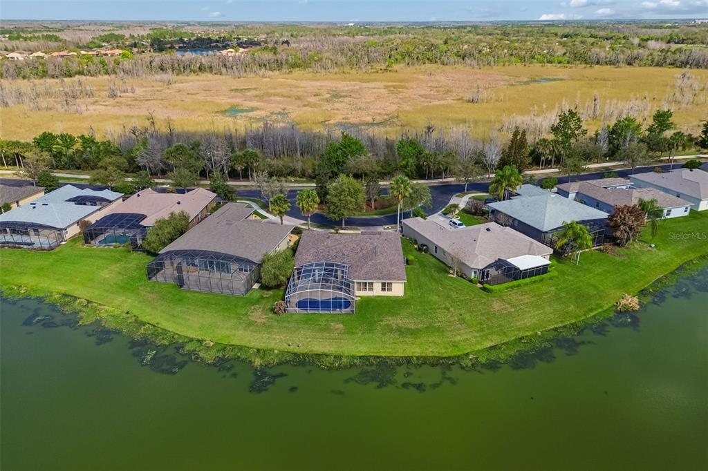 An aerial view shows several suburban houses with screened-in pools along a lakefront — 813 GLENDORA ROAD, KISSIMMEE, FL