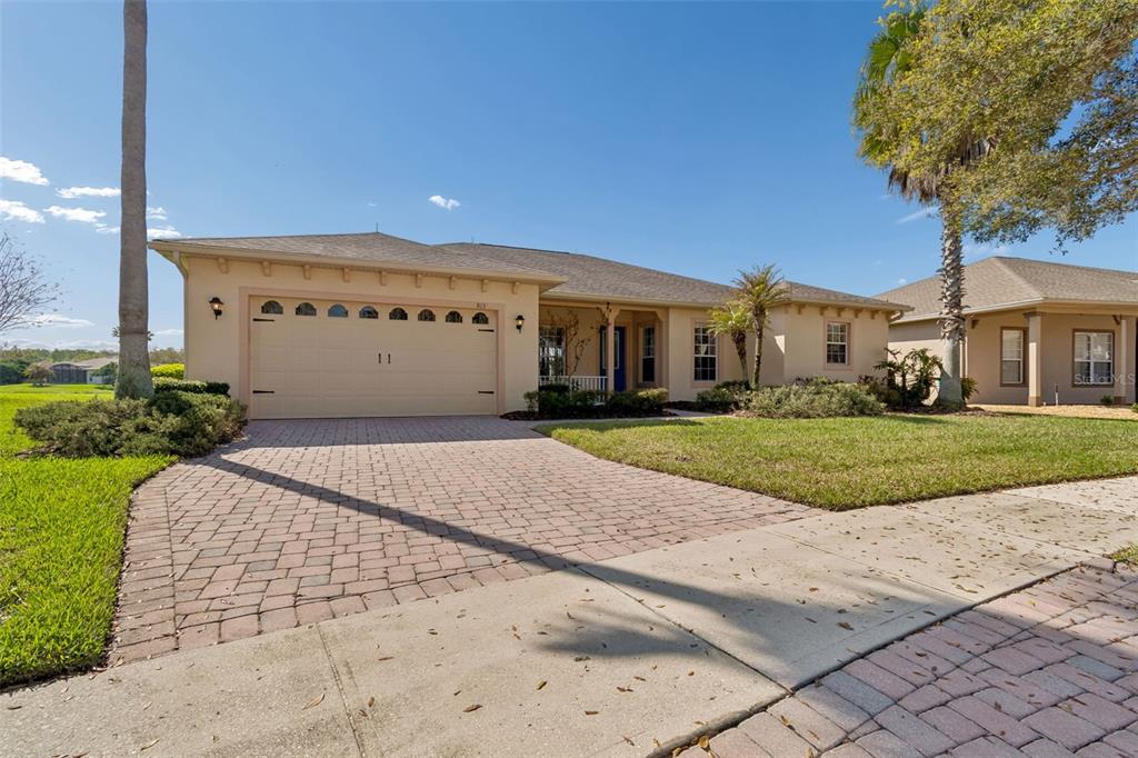 A single-story house with a beige exterior, a two-car garage, and a paved driveway — 813 GLENDORA ROAD, KISSIMMEE, FL