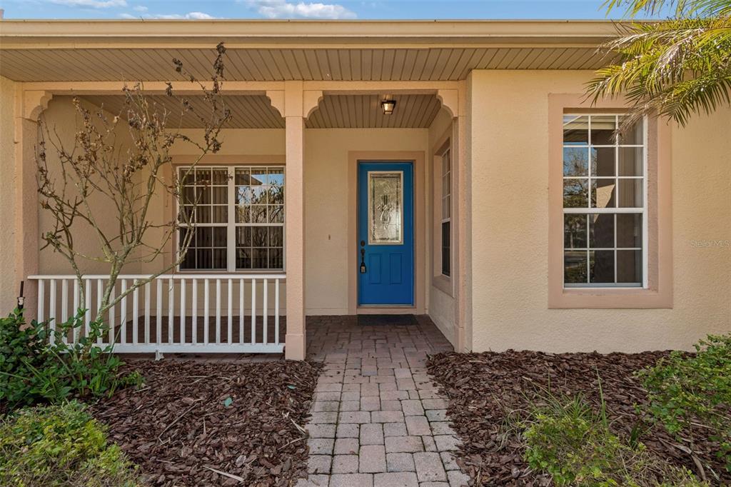 A front porch with a blue door, white railing, and a paver walkway — 813 GLENDORA ROAD, KISSIMMEE, FL