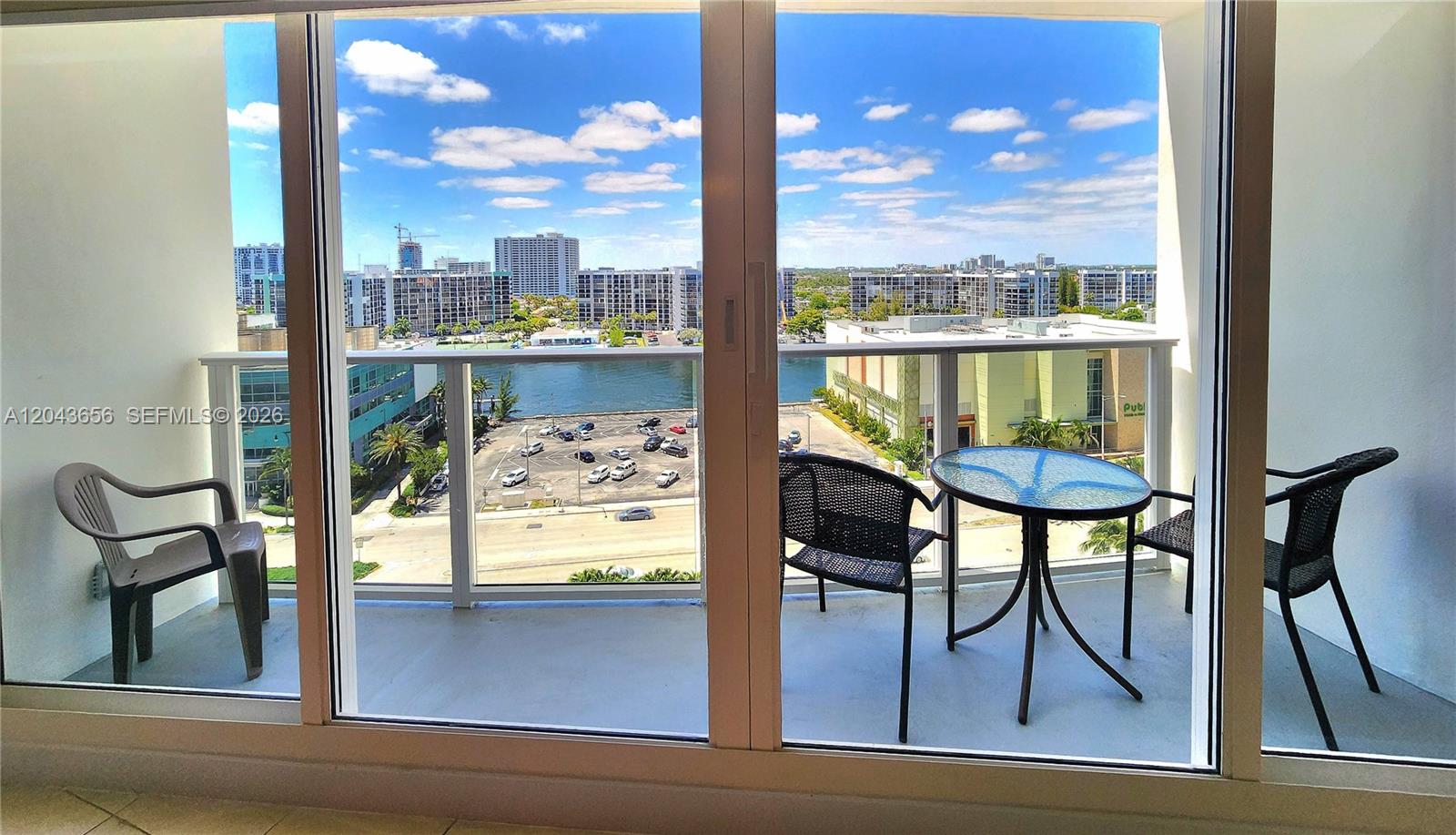 A balcony with outdoor furniture overlooks a parking lot, a waterway, and city buildings — 3505 S Ocean Dr # 1103, Hollywood FL 33019, HOLLYWOOD, FL