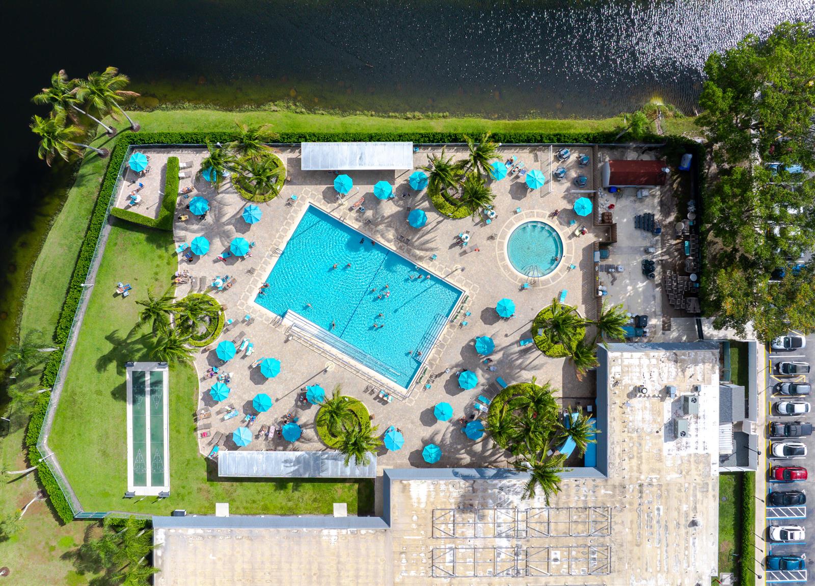 An aerial view shows a swimming pool, a hot tub, and a shuffleboard court outdoors — 233 Brittany E, Delray Beach FL 33446, DELRAY BEACH, FL