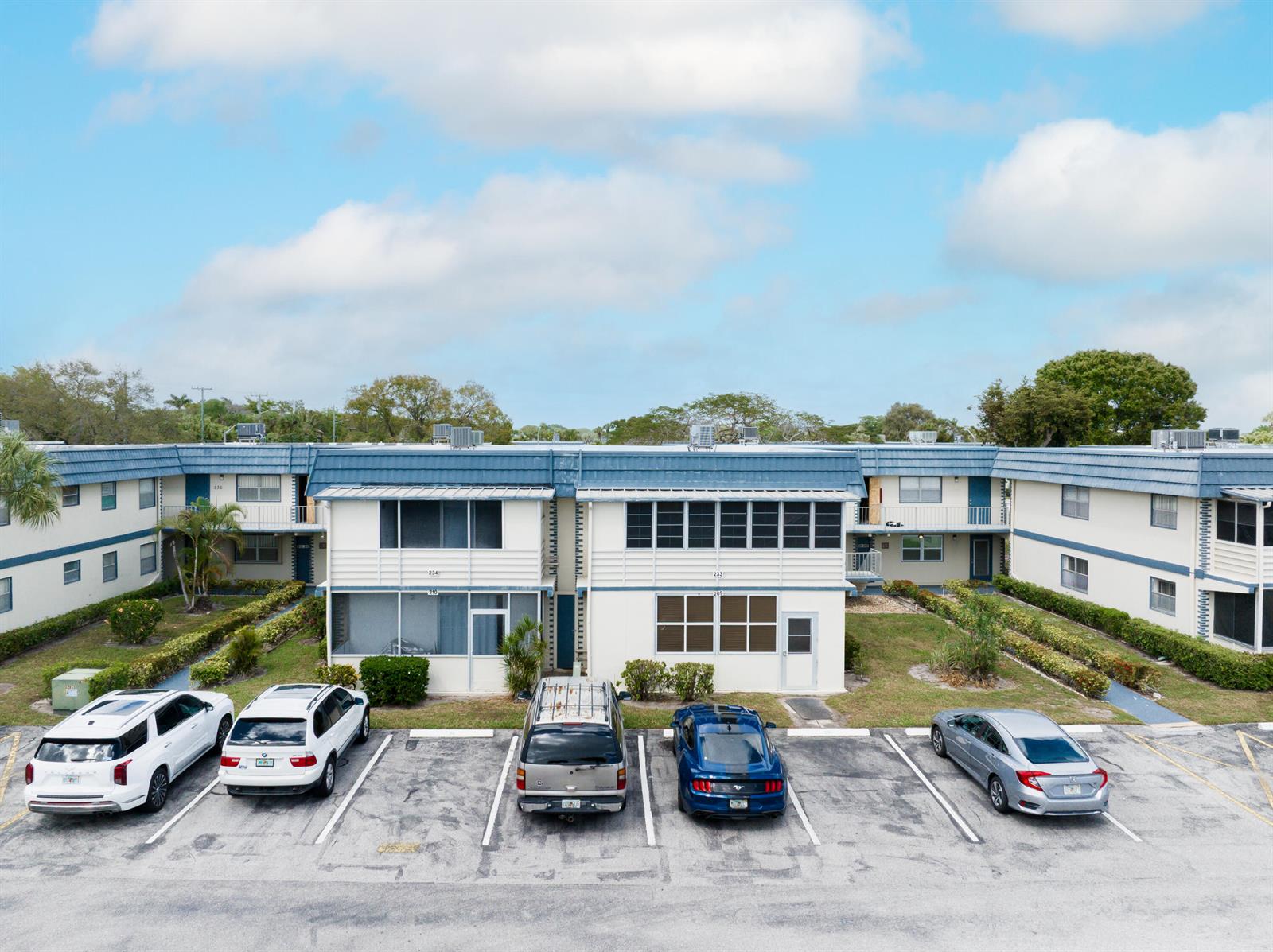 An exterior view of a two-story apartment building with a parking lot in front — 233 Brittany E, Delray Beach FL 33446, DELRAY BEACH, FL