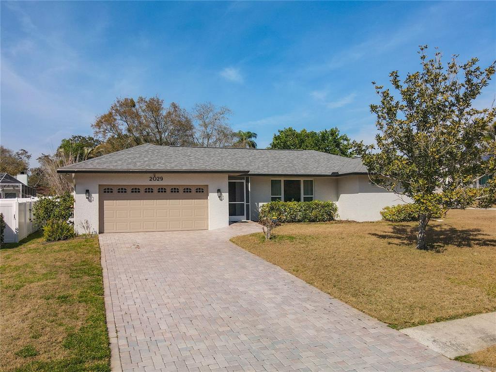 A single-story house with a tan garage, a paved driveway, and a light-colored exterior — 2029 SPANISH PINES DRIVE, DUNEDIN, FL