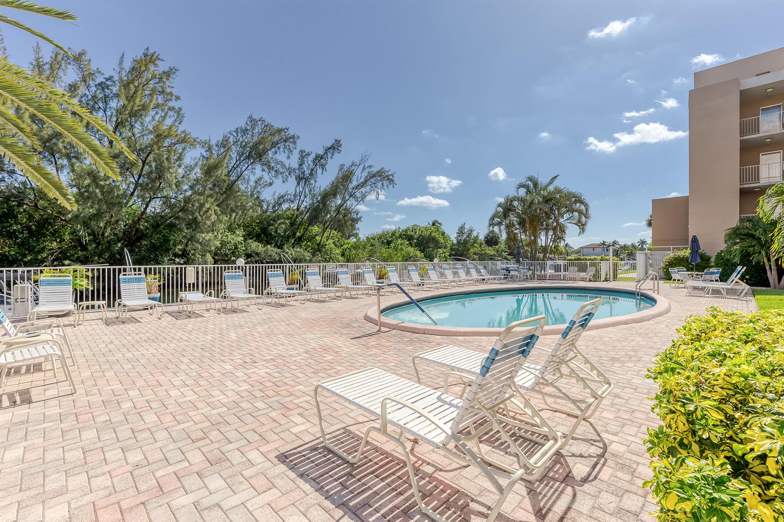 A swimming pool surrounded by lounge chairs on a brick patio next to a building — 2850 NE 14th St Causeway # 308b, Pompano Beach FL 33062, POMPANO BEACH, FL