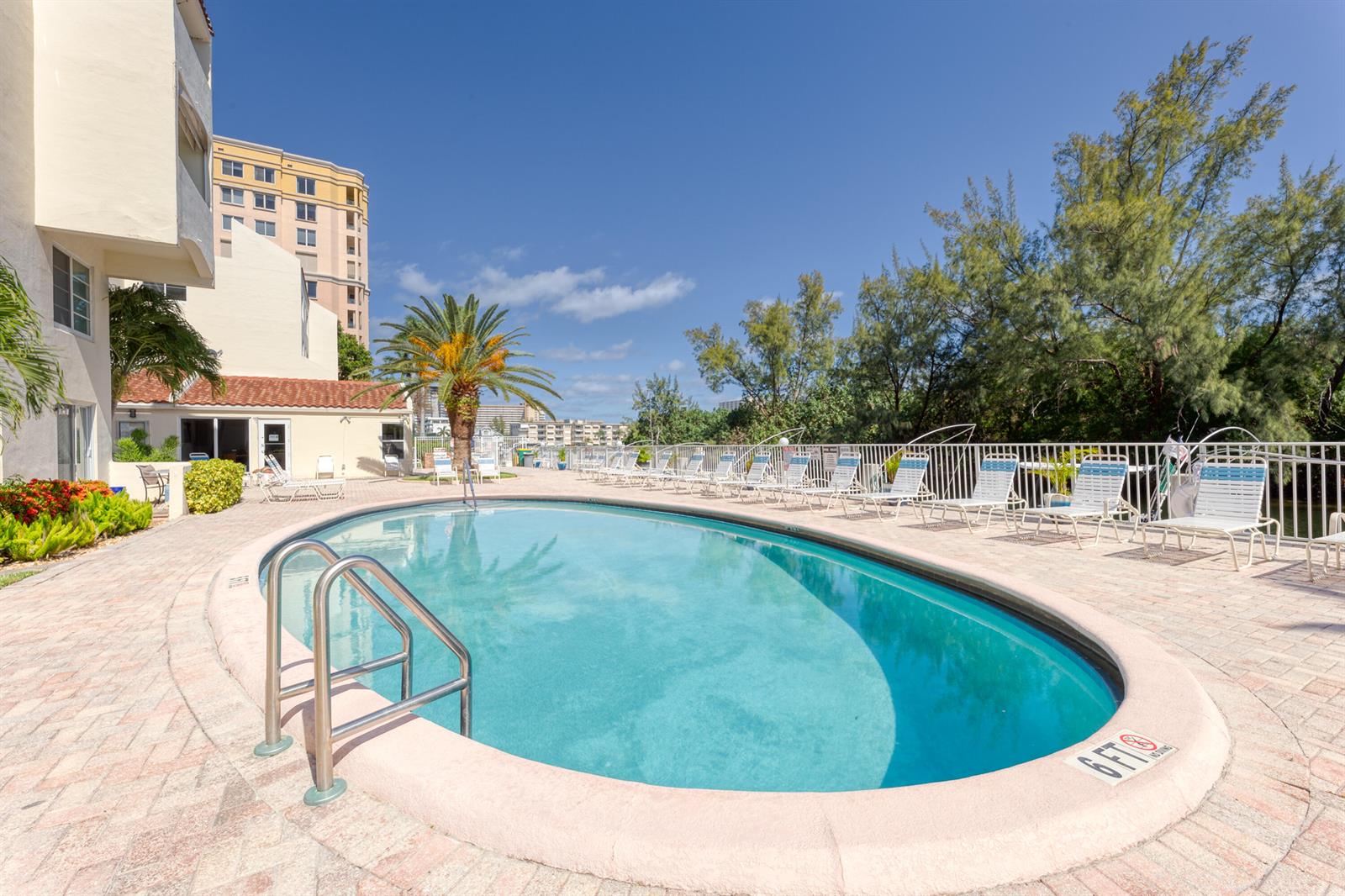An oval swimming pool with a metal ladder sits on a brick patio with lounge chairs — 2850 NE 14th St Causeway # 308b, Pompano Beach FL 33062, POMPANO BEACH, FL