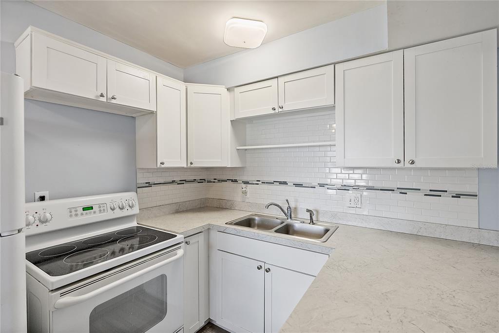 A kitchen with white cabinets, a white electric stove, and a light-colored countertop — 6266 1ST AVENUE S UNIT 29, ST PETERSBURG, FL
