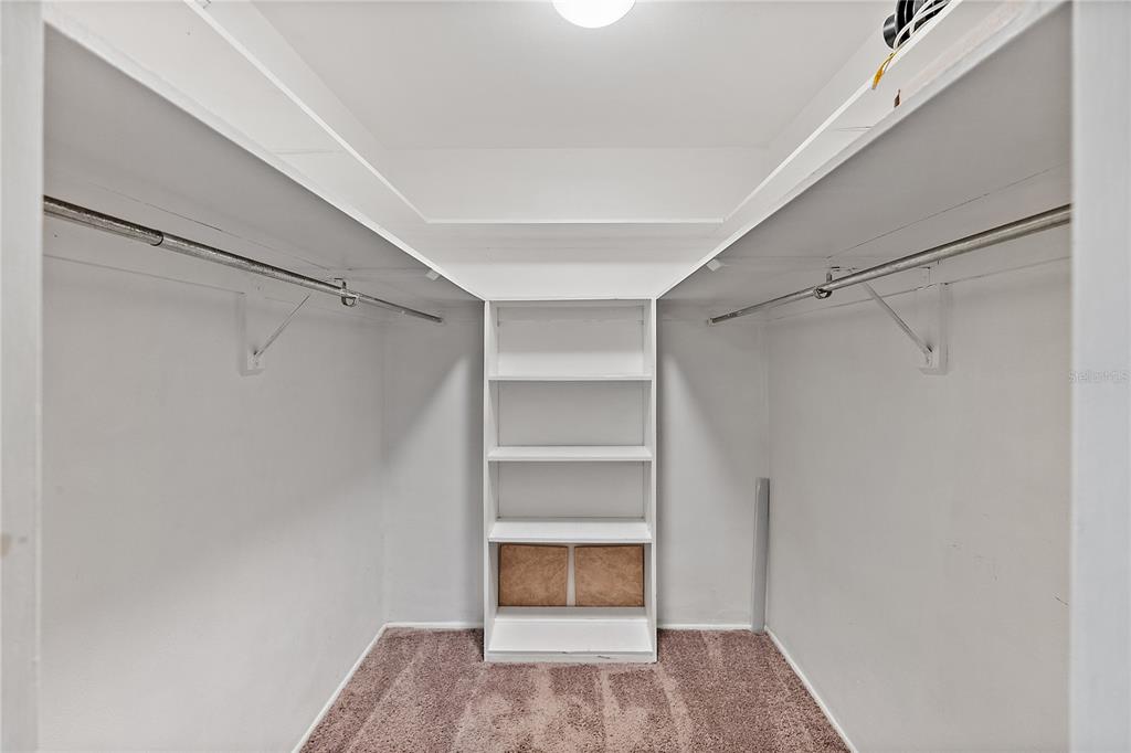 A walk-in closet features white shelving, dual hanging rods, and brown carpeted flooring — 6266 1ST AVENUE S UNIT 29, ST PETERSBURG, FL
