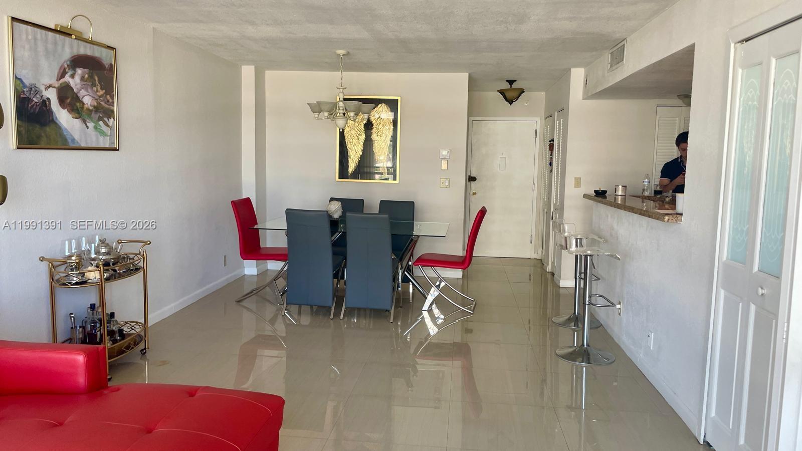 A dining area with a glass table, red and grey chairs, and a bar counter — 2017 OCEAN DR # 405W, Hallandale Beach FL 33009, HALLANDALE BEACH, FL