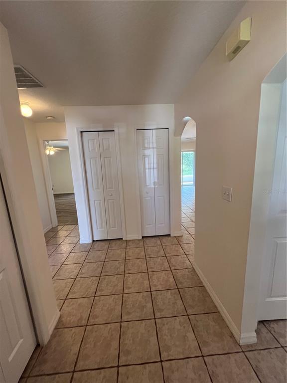 A hallway with tiled floors features two sets of white bifold closet doors — 3364 CELENA CIRCLE, ST CLOUD, FL