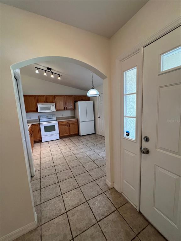 An arched entryway leads into a kitchen with wood cabinets, white appliances, and tiled floors — 3364 CELENA CIRCLE, ST CLOUD, FL