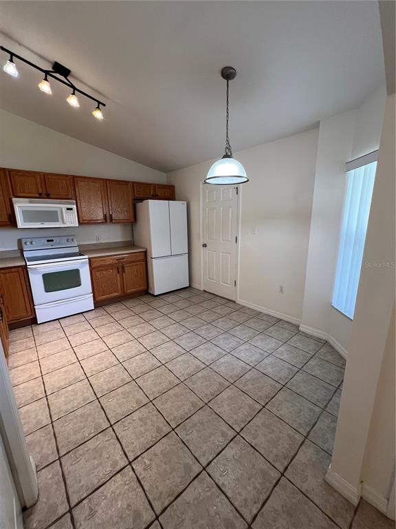 A kitchen features wood cabinets, white appliances, tile flooring, and a pendant light fixture — 3364 CELENA CIRCLE, ST CLOUD, FL