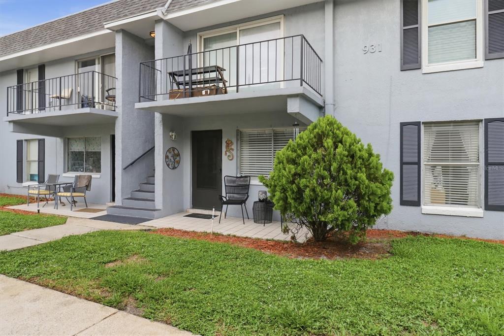 The exterior of a two-story apartment building features a balcony, stairs, and a small patio — 931 W OAK RIDGE ROAD UNIT B, ORLANDO, FL