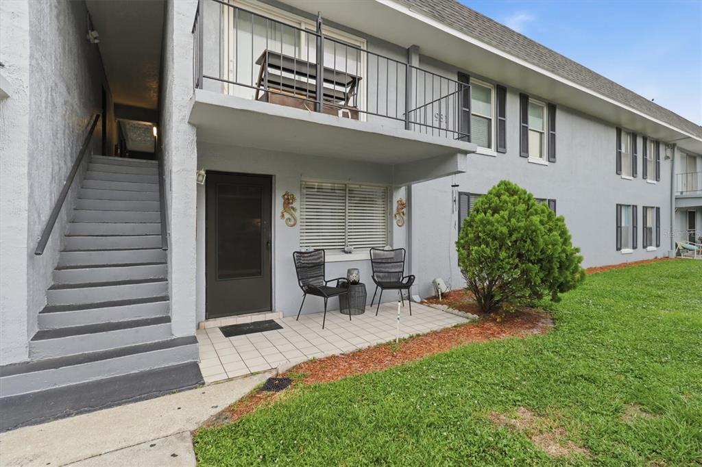 A ground-floor apartment patio with two chairs and a table sits below a balcony — 931 W OAK RIDGE ROAD UNIT B, ORLANDO, FL