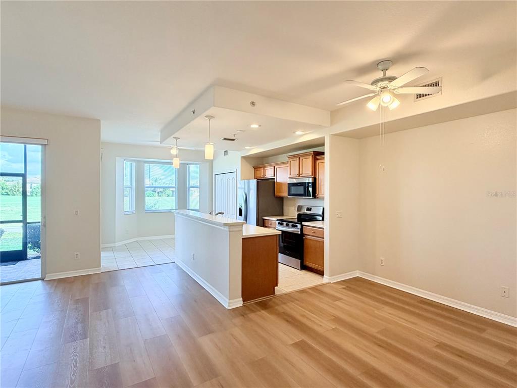 A kitchen with wood cabinets and a breakfast bar opens to a dining area — 819 FAIRWAYCOVE LANE UNIT 102, BRADENTON, FL