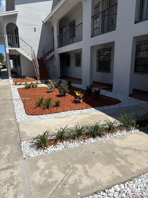 An exterior view of a multi-story apartment building with a landscaped courtyard and staircases — 1460 N 43rd Pl # 106, Hialeah FL 33012, HIALEAH, FL