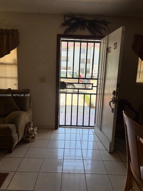 A living room with tiled floors features a sofa and an open door with security bars — 1460 N 43rd Pl # 106, Hialeah FL 33012, HIALEAH, FL