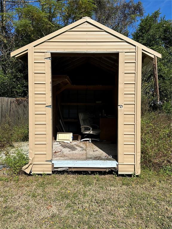 A tan metal storage shed stands outdoors with its double doors open — TBD NW 125TH PLACE, CITRA, FL