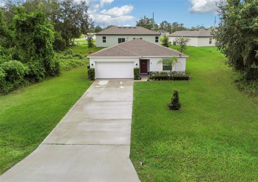 A single-story house with a white exterior, a two-car garage, and a concrete driveway — 320 ST CLOUD ROAD, POINCIANA, FL