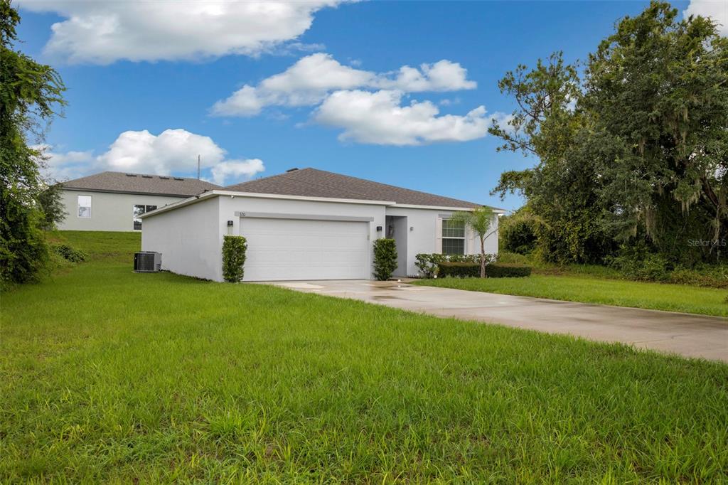 A single-story house with a white exterior, a two-car garage, and a concrete driveway — 320 ST CLOUD ROAD, POINCIANA, FL