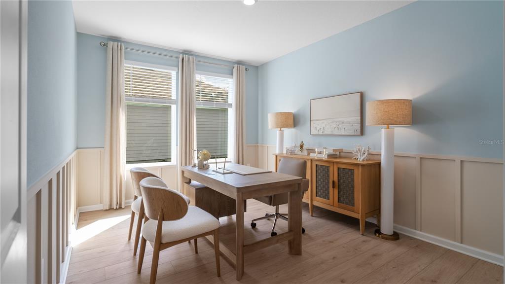 A home office features light blue walls, wood flooring, a desk, chairs, and two floor lamps — 3141 ROCKWOOD WAY, MINNEOLA, FL