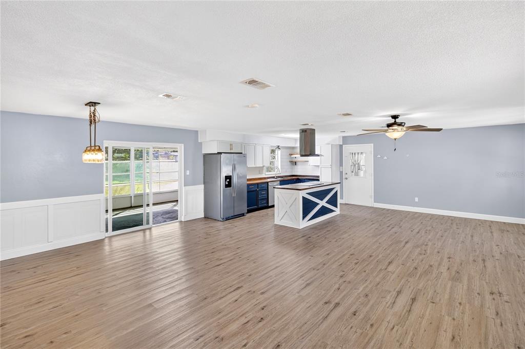 A spacious open-concept kitchen and living area featuring light wood flooring and a blue island — 3321 NW 28TH PLACE, GAINESVILLE, FL
