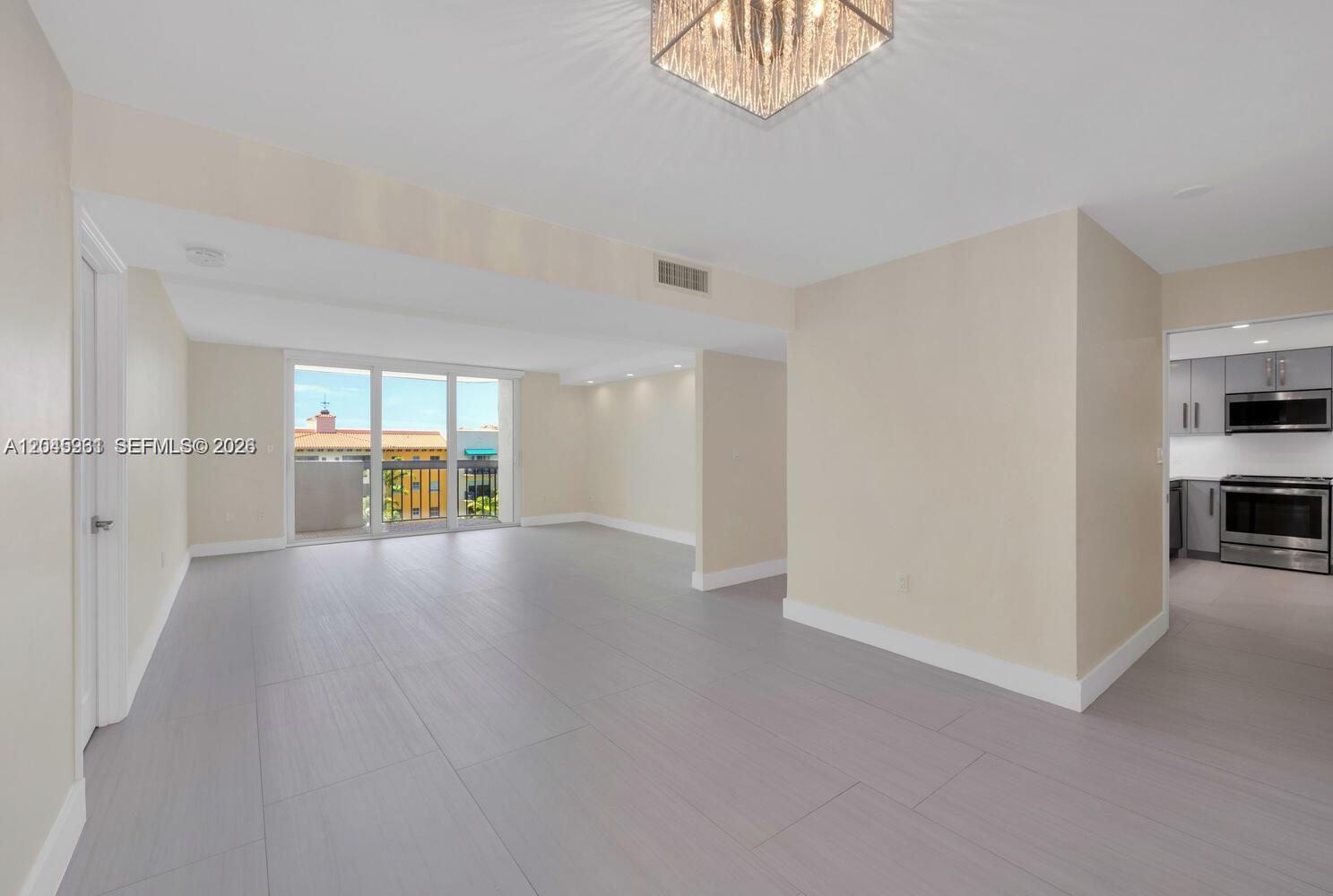 An open-concept living area features light gray tile flooring, a modern chandelier, and a kitchen — 600 Biltmore Way # 618, Coral Gables FL 33134, CORAL GABLES, FL