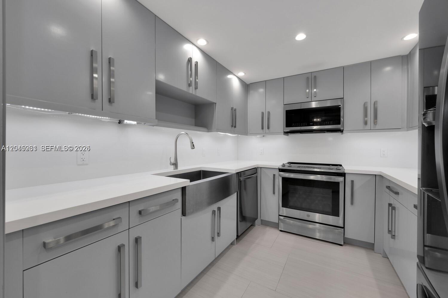 A modern kitchen features gray flat-panel cabinets, stainless steel appliances, and white quartz countertops — 600 Biltmore Way # 618, Coral Gables FL 33134, CORAL GABLES, FL