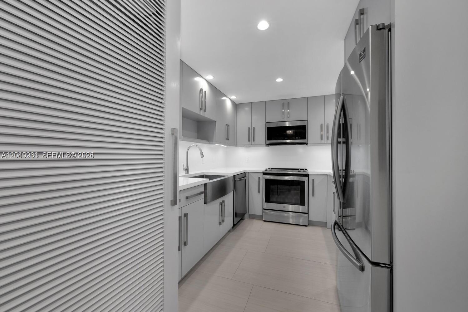 A modern galley kitchen features gray cabinetry, stainless steel appliances, and white countertops — 600 Biltmore Way # 618, Coral Gables FL 33134, CORAL GABLES, FL