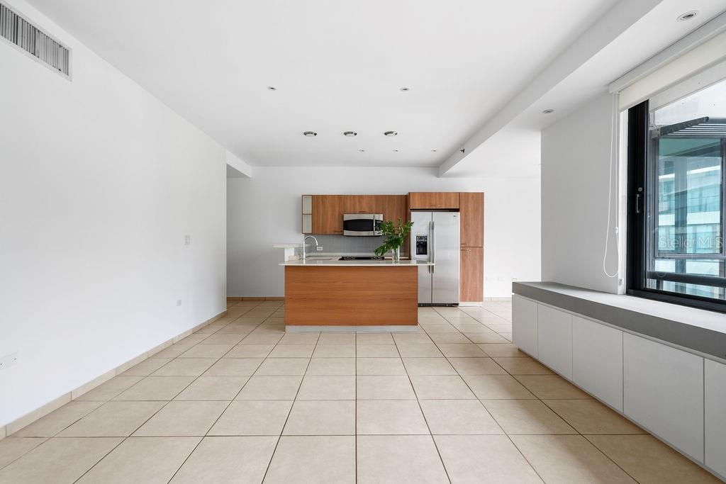 A kitchen with wood cabinets and a center island sits in an open-plan room — 1511 PONCE DE LEON AVENUE UNIT 473, SAN JUAN, PR
