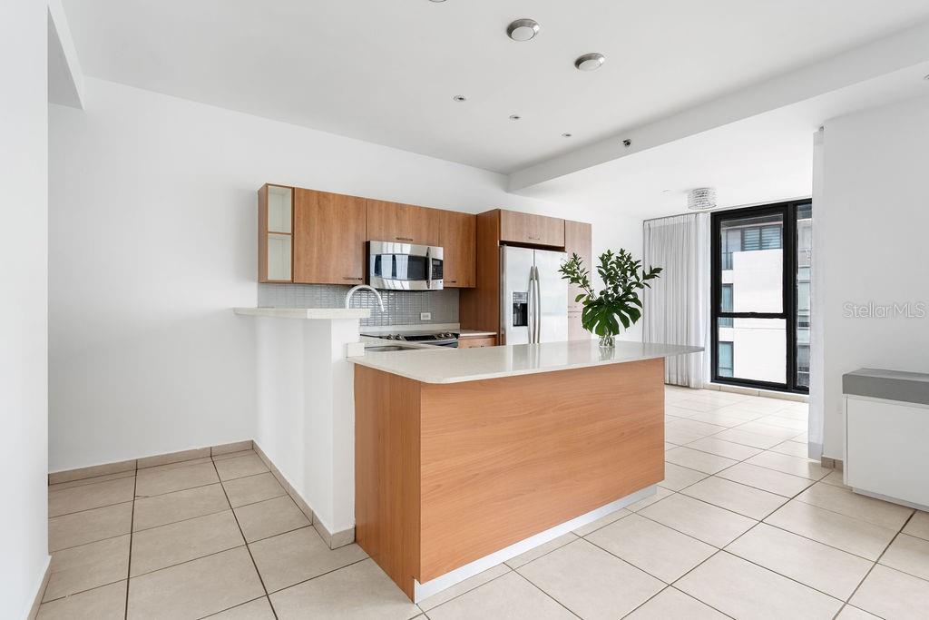 A modern kitchen features light wood cabinets, a white island, and tile flooring — 1511 PONCE DE LEON AVENUE UNIT 473, SAN JUAN, PR