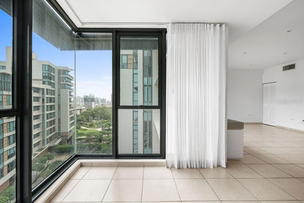 A bright room with tiled floors, floor-to-ceiling windows, and a view of city buildings — 1511 PONCE DE LEON AVENUE UNIT 473, SAN JUAN, PR