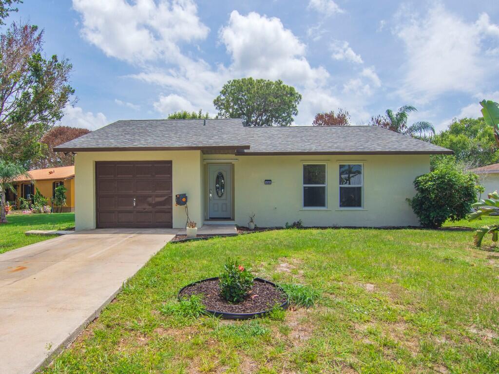 A single-story house with a light yellow exterior, a brown garage door, and a concrete driveway — 4065 46th Lane, Vero Beach FL 32967, VERO BEACH, FL