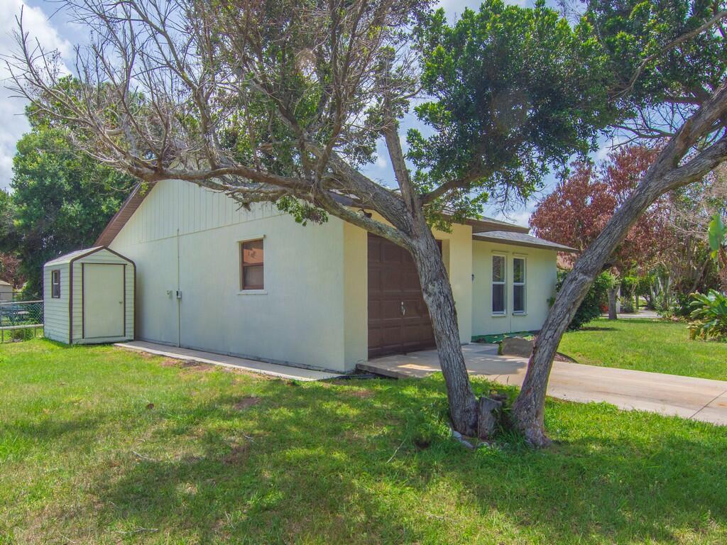 A light-colored house with a brown garage door, a side shed, and a large tree — 4065 46th Lane, Vero Beach FL 32967, VERO BEACH, FL