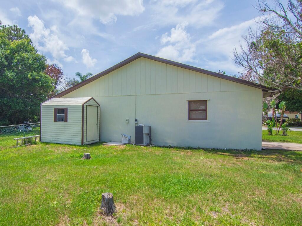 A side view of a house with a shed, an air conditioning unit, and grass — 4065 46th Lane, Vero Beach FL 32967, VERO BEACH, FL