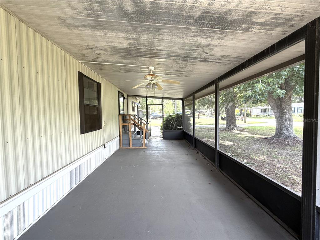 A covered, screened-in porch features a concrete floor, a ceiling fan, and exterior siding — 1355 N REED TERRACE, INVERNESS, FL