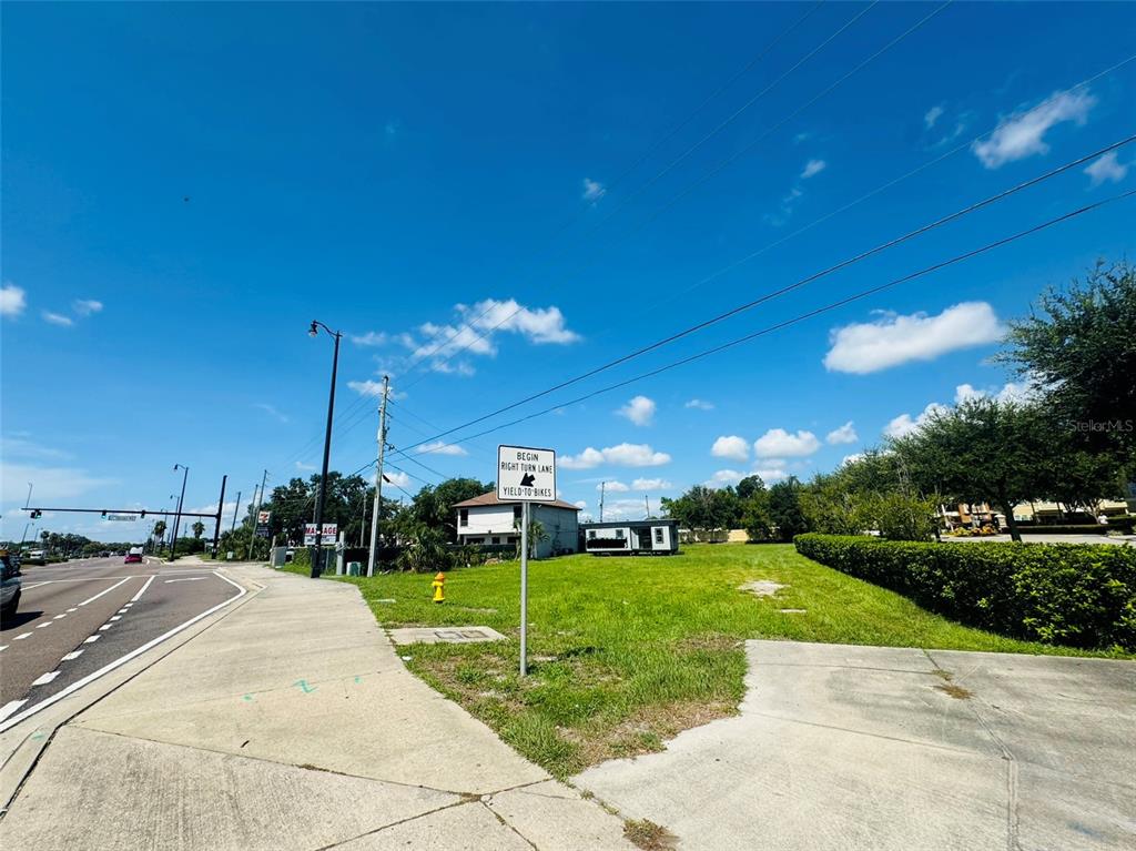 A vacant grassy lot sits next to a sidewalk with a road and traffic sign — 8390 S US HIGHWAY 17-92 HIGHWAY UNIT 1001-1009, FERN PARK, FL