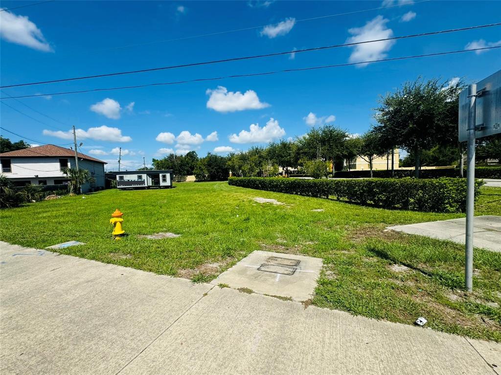 A vacant grassy lot features a fire hydrant and a concrete utility cover — 8390 S US HIGHWAY 17-92 HIGHWAY UNIT 1001-1009, FERN PARK, FL