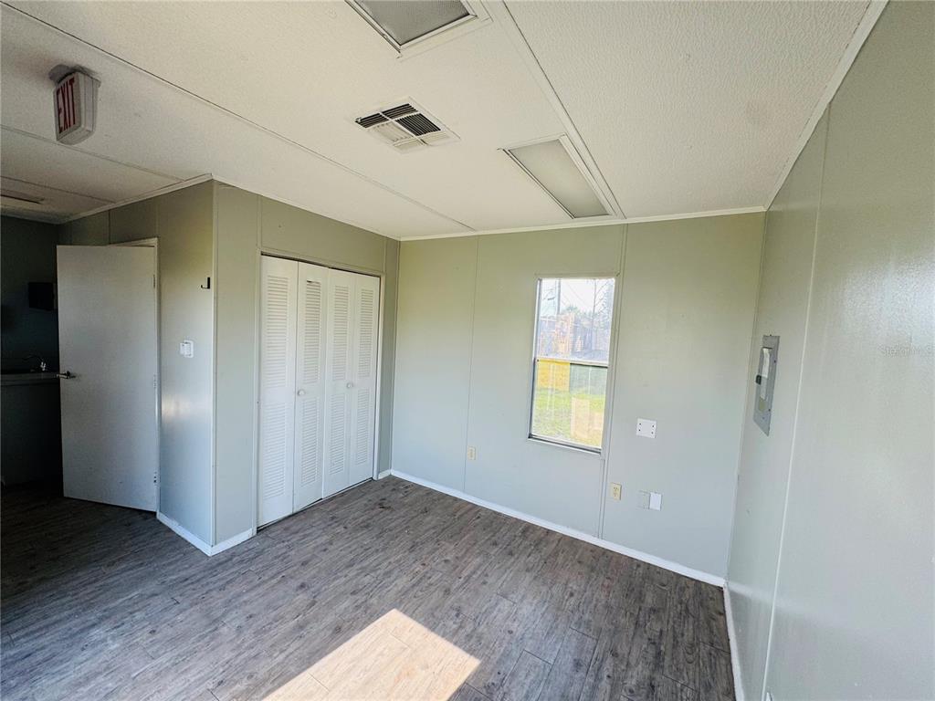 An empty room features light-colored walls, wood-look flooring, a closet with white doors, and a window — 8390 S US HIGHWAY 17-92 HIGHWAY UNIT 1001-1009, FERN PARK, FL