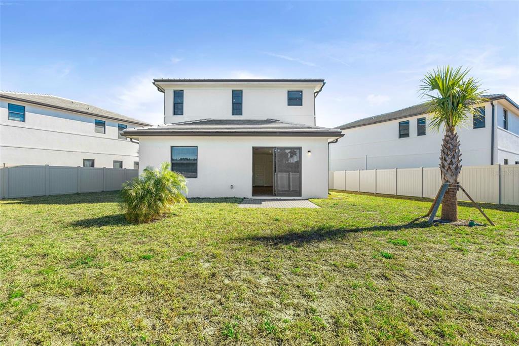 The backyard of a two-story white house features a small patio and a palm tree — 8044 GULFSTREAM COURT UNIT 14318, LAKEWOOD RANCH, FL