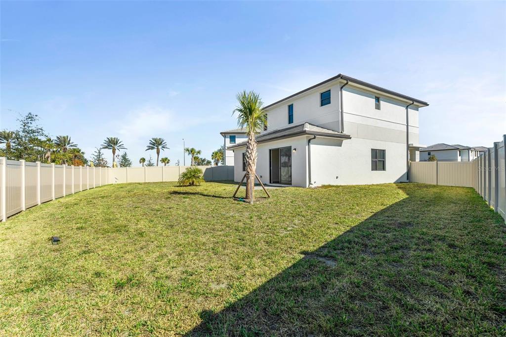 The backyard of a two-story house features a small palm tree and vinyl fencing — 8044 GULFSTREAM COURT UNIT 14318, LAKEWOOD RANCH, FL