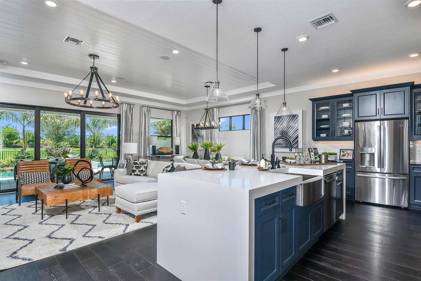 A modern open-concept kitchen and living area features blue cabinetry, a white island, and patio — 5633 Saint Armands Way, Westlake FL 33470, WESTLAKE, FL