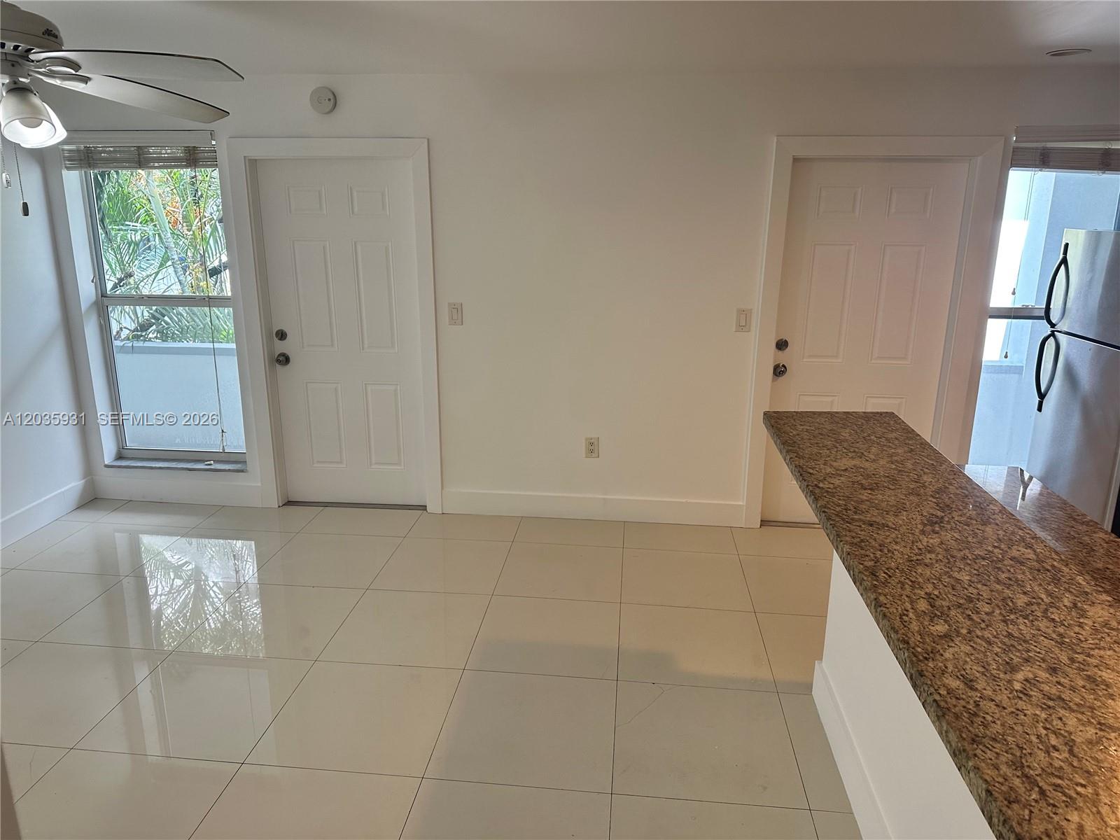 A bright room features white walls, tiled floors, two white doors, and a granite countertop — 3071 SW 27th Ave # 25, Miami FL 33133, MIAMI, FL