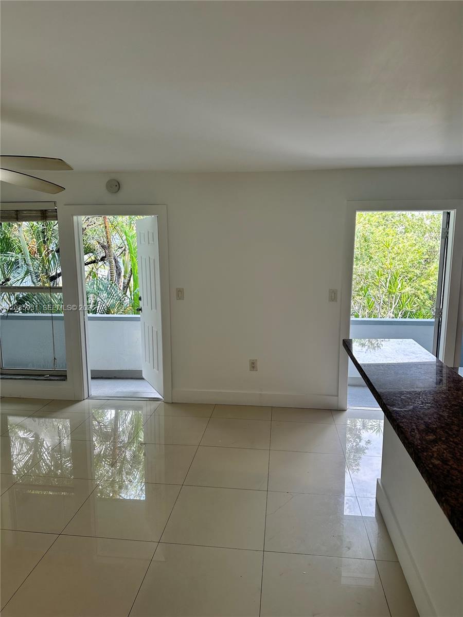 A room with light tile flooring, white walls, and two doors leading to a balcony — 3071 SW 27th Ave # 25, Miami FL 33133, MIAMI, FL